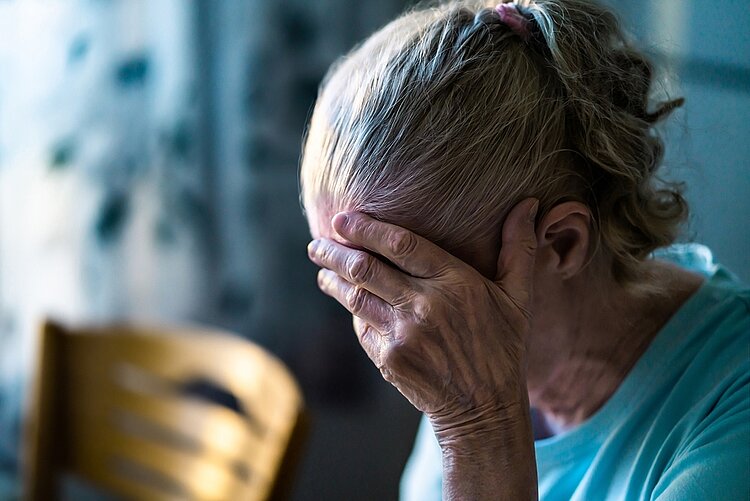 Altersdiskriminierung in Deutschland Eine ältere Frau mit grauem Haar hält verzweifelt die Hand vor das Gesicht.