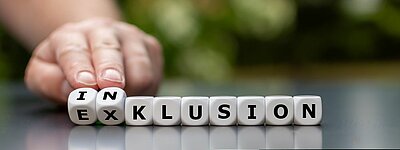 Unterschied zwischen Exklusion, Integration und Inklusion – und warum es mehr als nur Worte sind Ein Hand bewegt einen Würfel mit der Aufschrift "IN" zu einem Wort, das "EXKLUSION" bildet.
